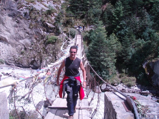 author hiking across swing bridge in Nepal